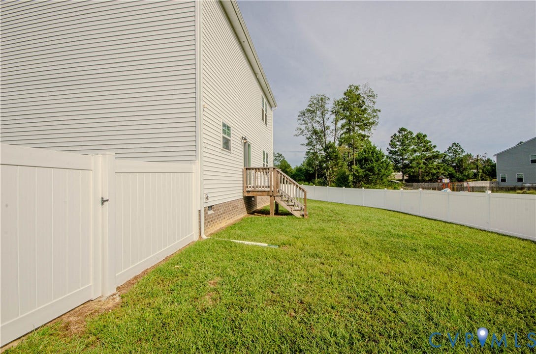 Expansive grassy, rear yard defined by white privacy fencing