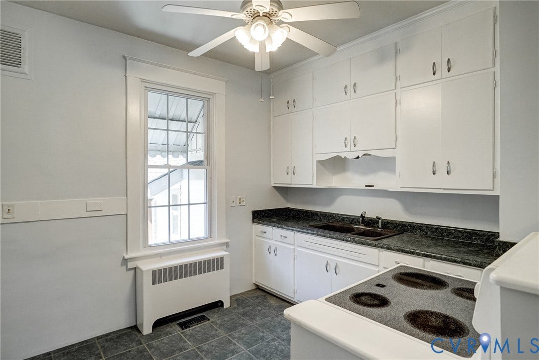 10024 Washington Road, Richmond, VA 23060 White cabinetry with silver-tone hardware, dark countertop with integrated double sink, white electric range, ceiling fan with integrated lighting, and a single window with white trim