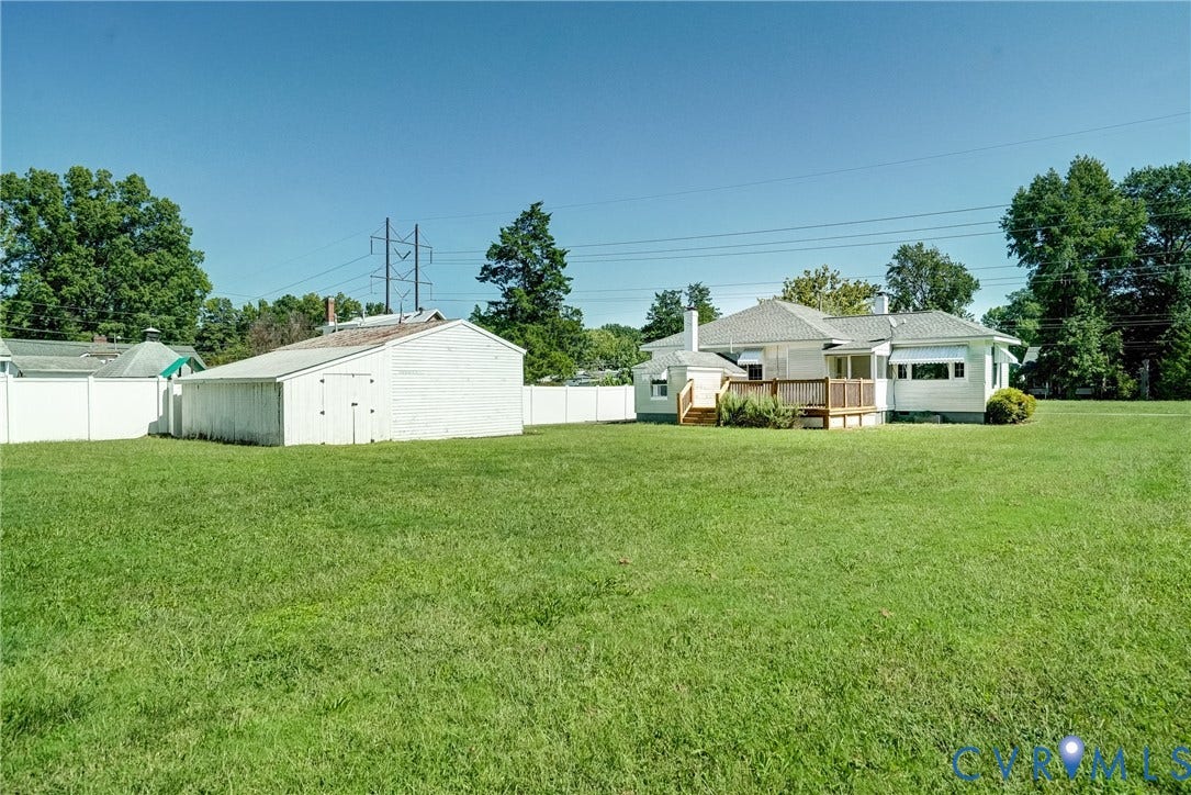 10024 Washington Road, Richmond, VA 23060 Expansive grassy lawn with a white privacy fence, a detached utility building, and a rear deck