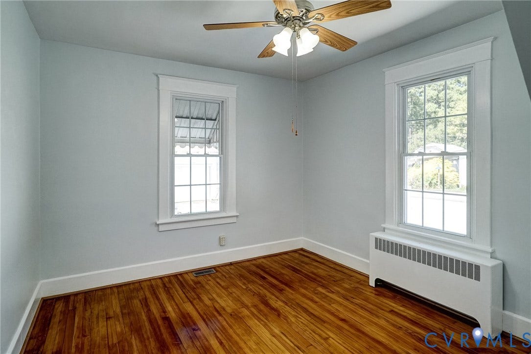10024 Washington Road, Richmond, VA 23060 Wood-finish flooring with white baseboards, natural light from two windows, and a ceiling fan