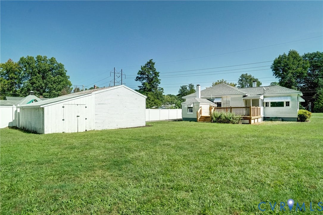 10024 Washington Road, Richmond, VA 23060 Expansive grassy yard with a white privacy fence, an outbuilding, and a wood deck with railings