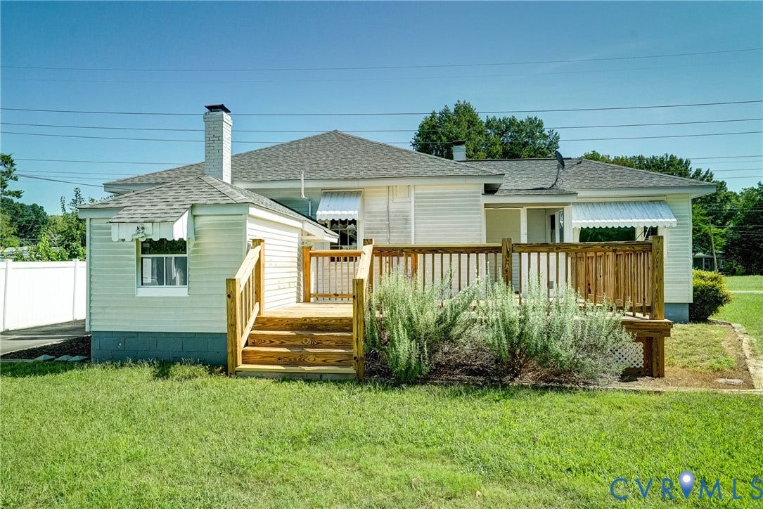 10024 Washington Road, Richmond, VA 23060 Expansive backyard featuring a new wooden deck with railings and steps, a white privacy fence, and a chimney with a metal cap