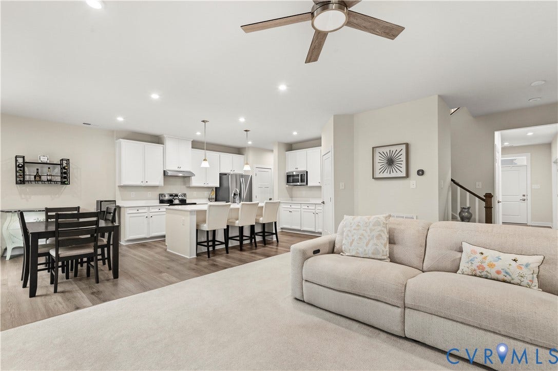 4837 Bacova Village Trail, Glen Allen, VA 23059 Open-concept layout featuring wood-finish flooring, recessed lighting, a modern ceiling fan, white kitchen cabinetry, and a kitchen island with pendant lighting