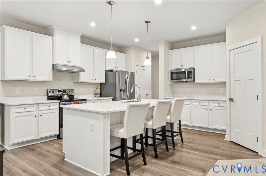 4837 Bacova Village Trail, Glen Allen, VA 23059 Kitchen featuring white cabinetry, light-toned countertops, a center island with pendant lighting, stainless steel appliances, and wood-finish flooring