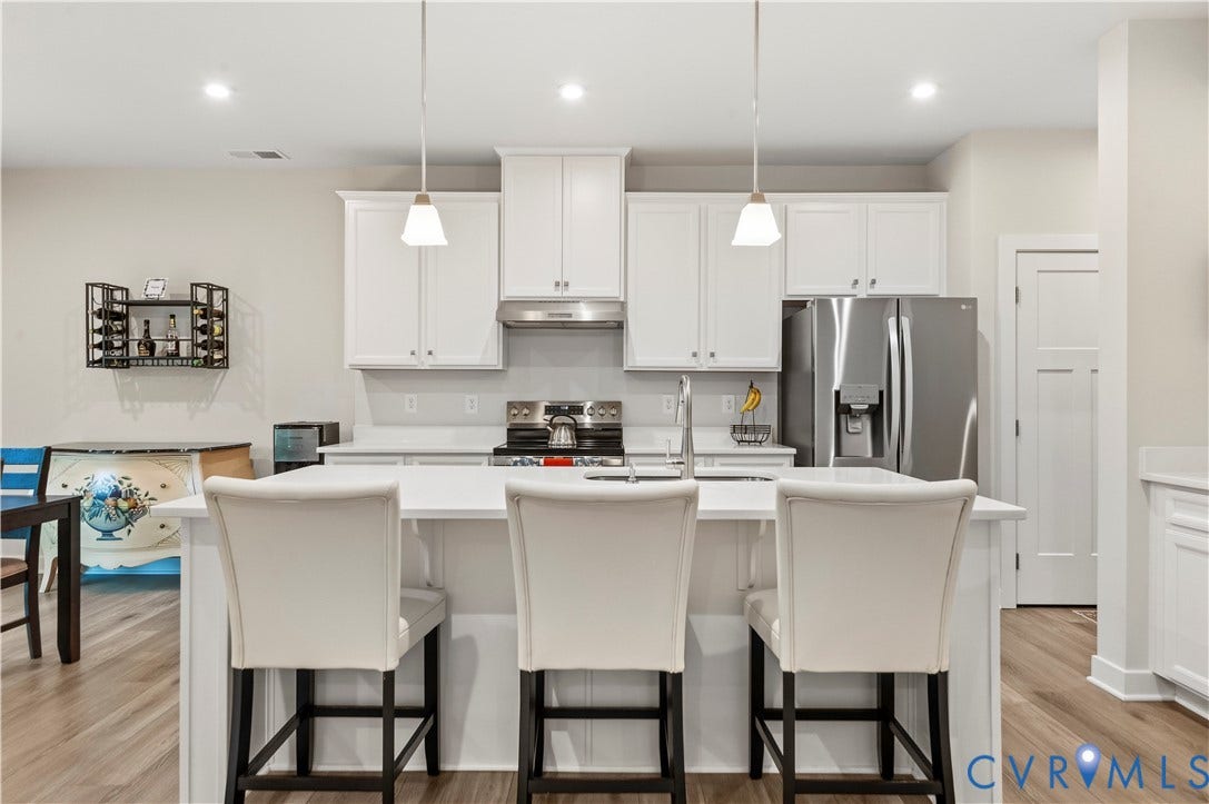 4837 Bacova Village Trail, Glen Allen, VA 23059 White shaker-style cabinetry with stainless steel appliances, a center island, pendant lighting, and wood-finish flooring
