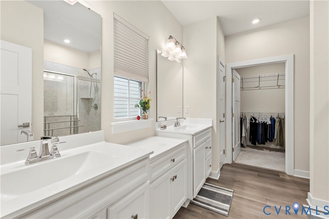 4837 Bacova Village Trail, Glen Allen, VA 23059 Dual vanity with white cabinetry, wood-finish flooring, a glass-enclosed shower, and a walk-in closet with wire shelving