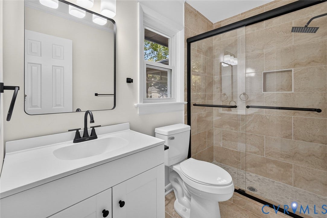 1122 Glidewell Road, Henrico, VA 23227 Bathroom featuring a white vanity with an integrated sink, matte black faucet, rectangular mirror, walk-in shower with stone-tile surround, and a glass enclosure with a black frame