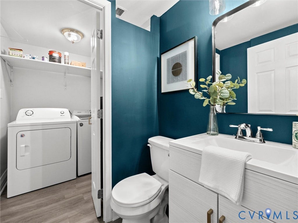 5112 Bethlehem Road, Libbie Mill Area, Richmond, VA 23230 Integrated laundry area with shelving, vanity with a white countertop and chrome fixtures, wood-finish flooring, and a wall-mounted mirror