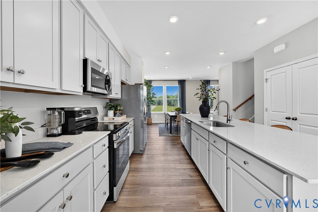 6126 Hull Street Road, Richmond, VA 23224 White shaker cabinetry with stainless steel appliances, light-toned countertops, wood-finish flooring, and recessed lighting
