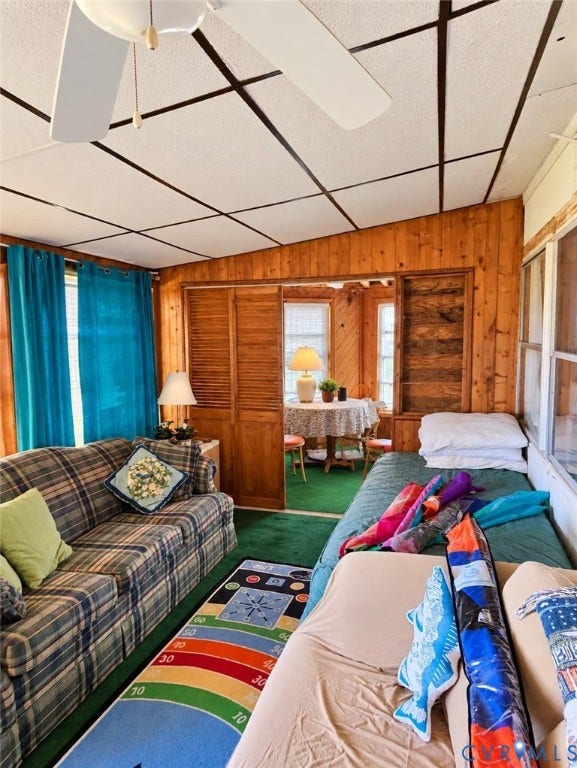 36 Beach Road, Reedville, VA 22539 Wood-paneled room featuring a ceiling fan, wall sconce, and louvered bifold doors