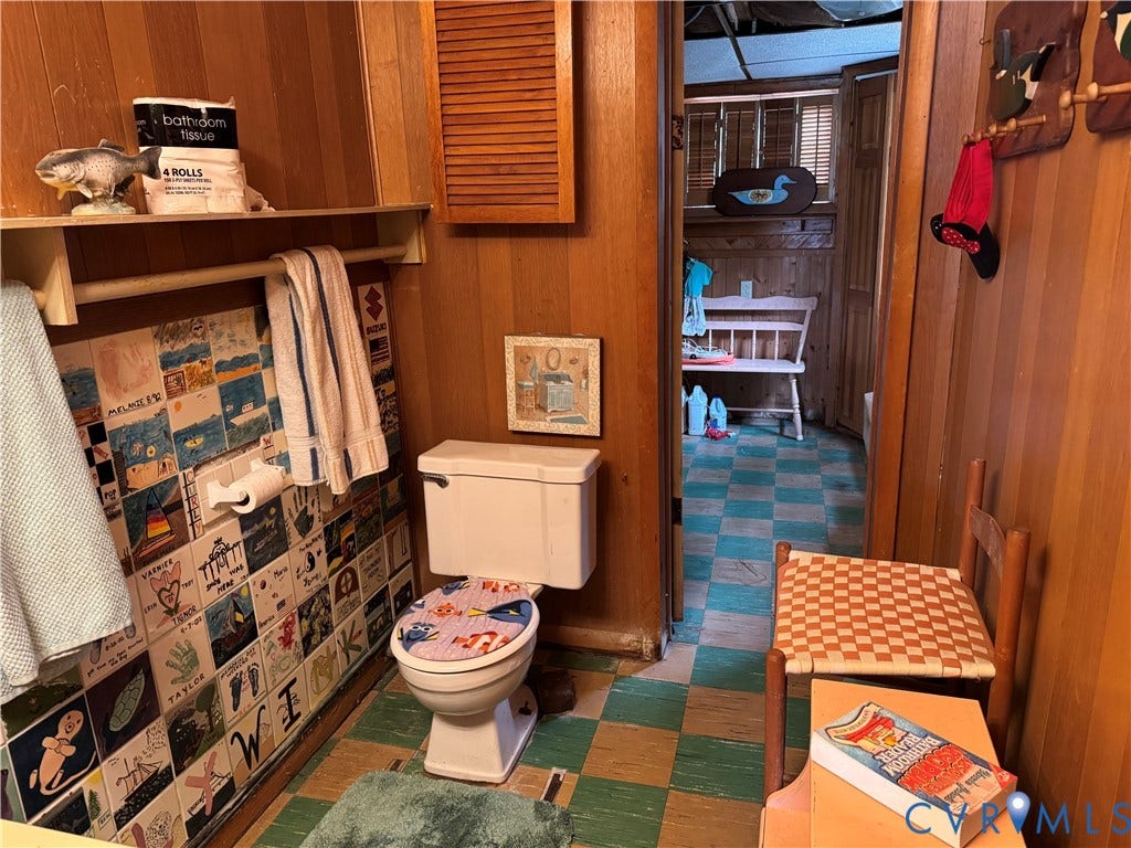 36 Beach Road, Reedville, VA 22539 Bathroom featuring wood-paneled walls, checkerboard-patterned flooring, and a decorative tile accent wall