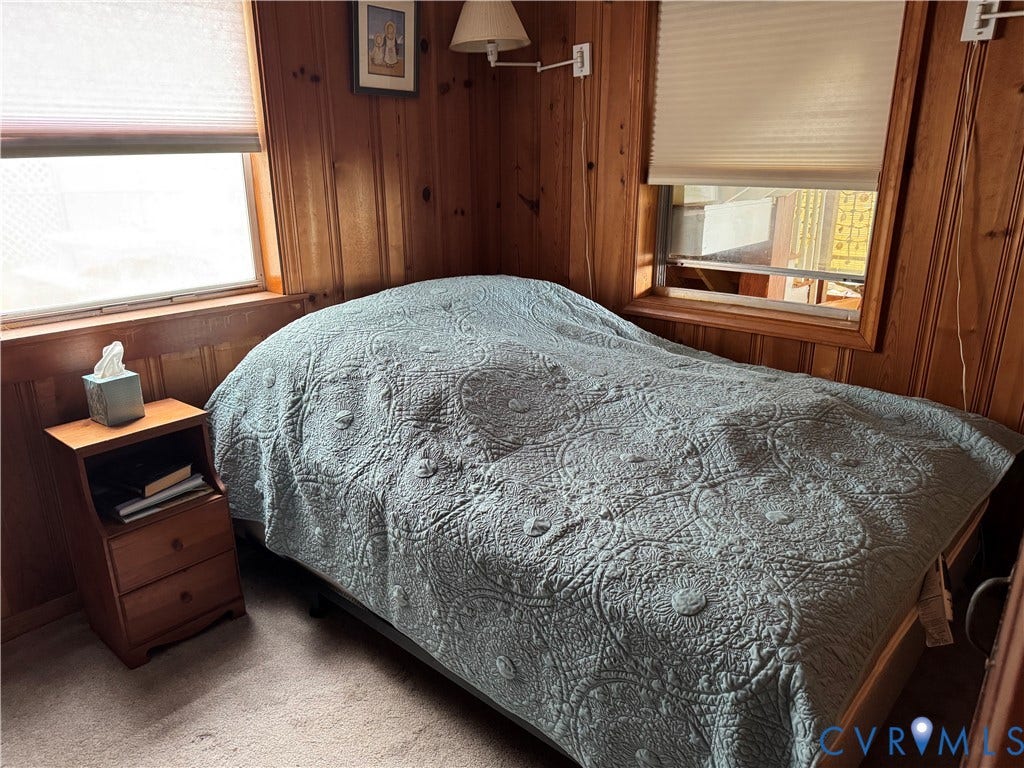 36 Beach Road, Reedville, VA 22539 Wood-paneled walls, two windows with pleated cellular shades, and wall-mounted swing-arm lamp