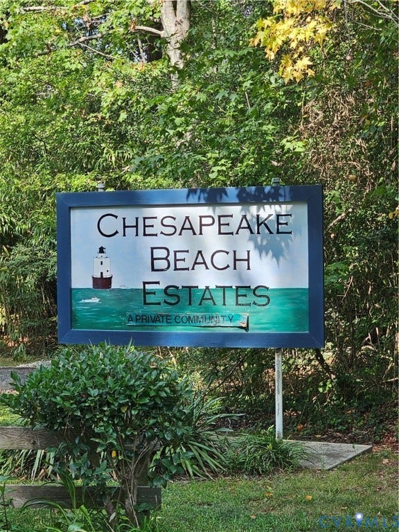 36 Beach Road, Reedville, VA 22539 "Chesapeake Beach Estates" community signage with a lighthouse graphic, framed by mature trees and manicured shrubbery