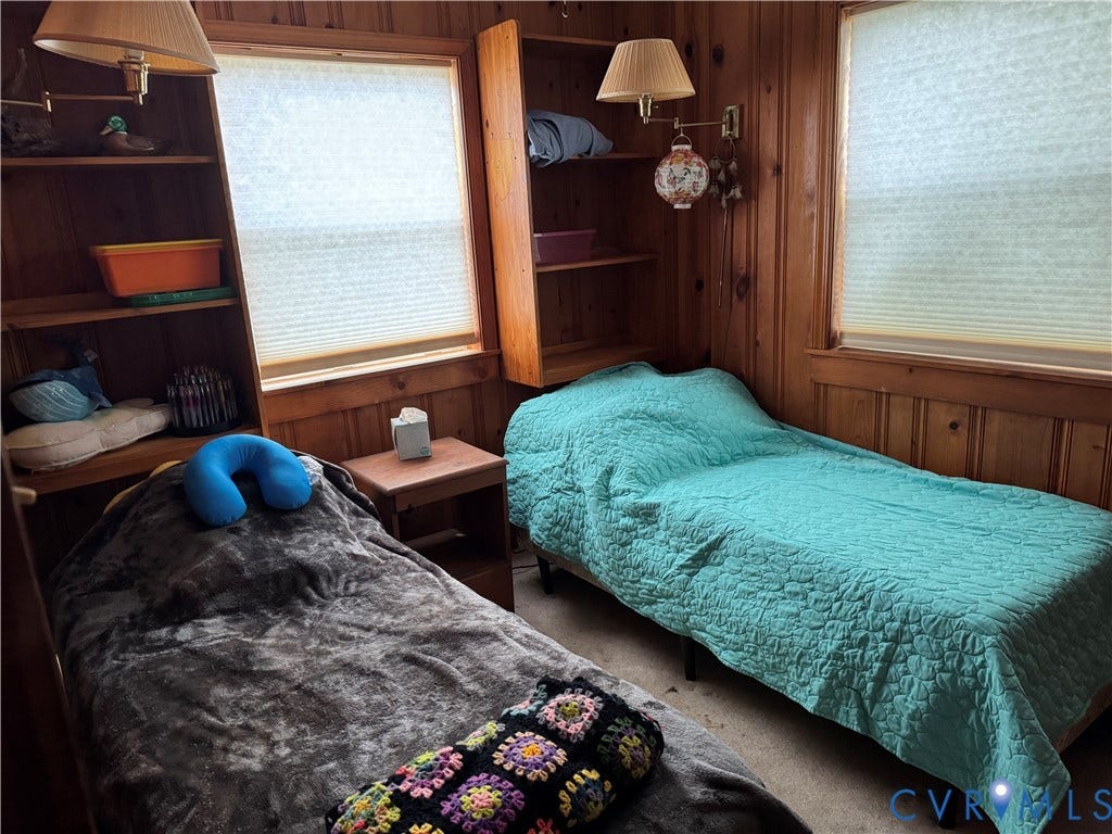 36 Beach Road, Reedville, VA 22539 Wood-paneled interior walls, two windows with integrated cellular shades, built-in shelving units, and two wall-mounted adjustable lamps