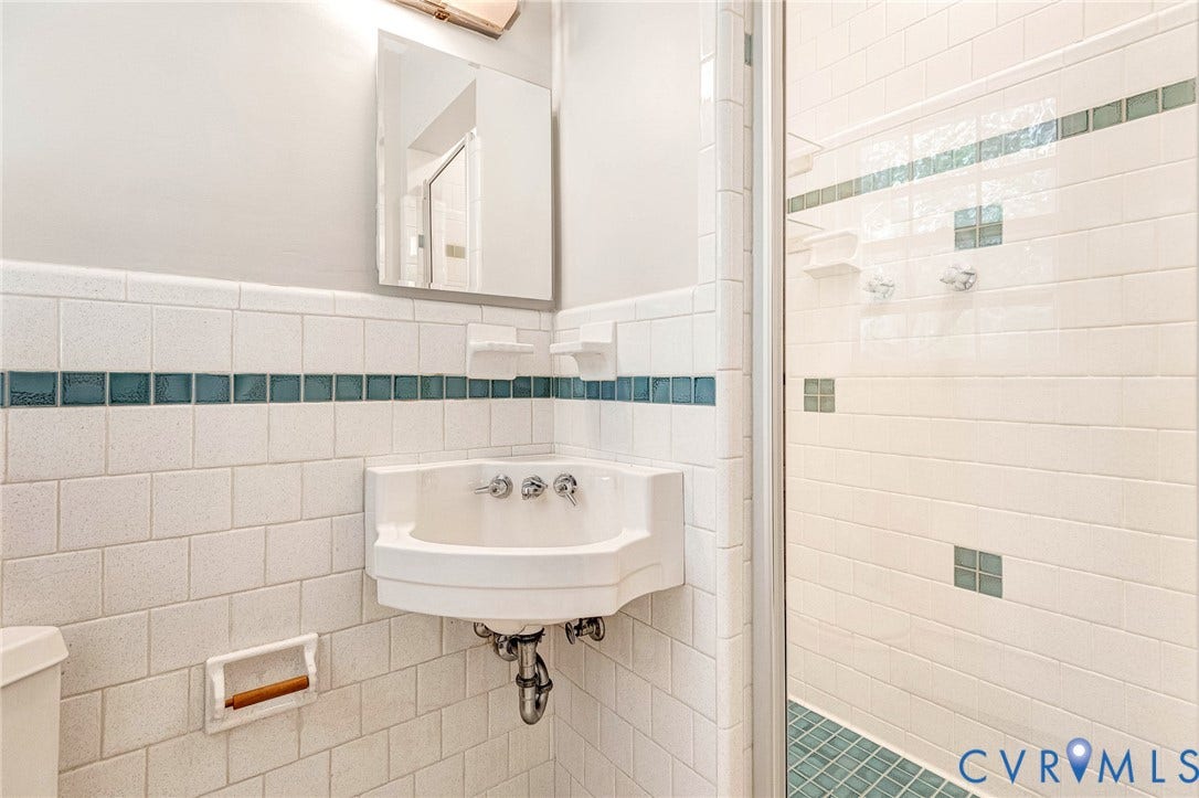 5215 Sprucewood Avenue, North Chesterfield, VA 23234 Corner sink vanity with white tile walls featuring a decorative teal accent band
