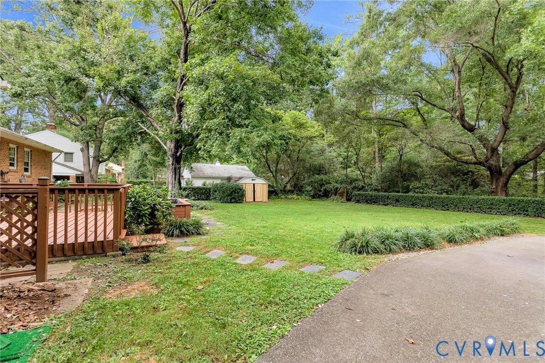 5215 Sprucewood Avenue, North Chesterfield, VA 23234 Expansive backyard featuring a wood deck, manicured lawn, stepping stones, and mature trees