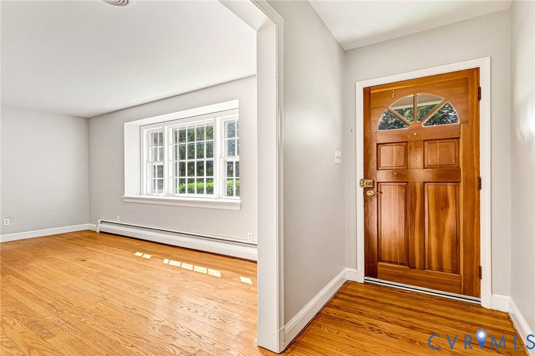 5215 Sprucewood Avenue, North Chesterfield, VA 23234 Warm wood-finish flooring throughout, bright paneled front door with an arched transom, and a multi-pane window with white trim