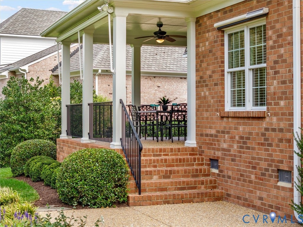 Brick exterior with a covered patio featuring white columns and a ceiling fan