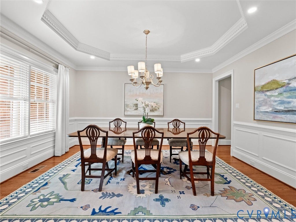Tray ceiling with decorative molding, recessed lighting, wood-finish flooring, wainscoting, and a chandelier