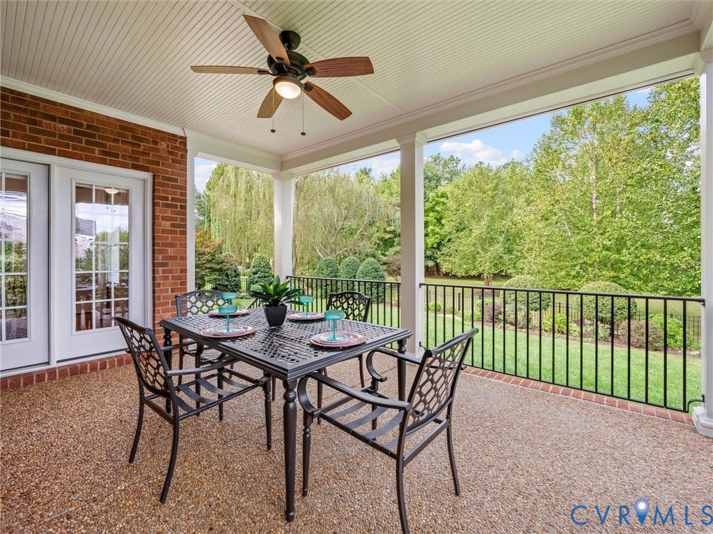 Covered patio with beadboard ceiling, exposed aggregate flooring, brick exterior, and wrought iron railing