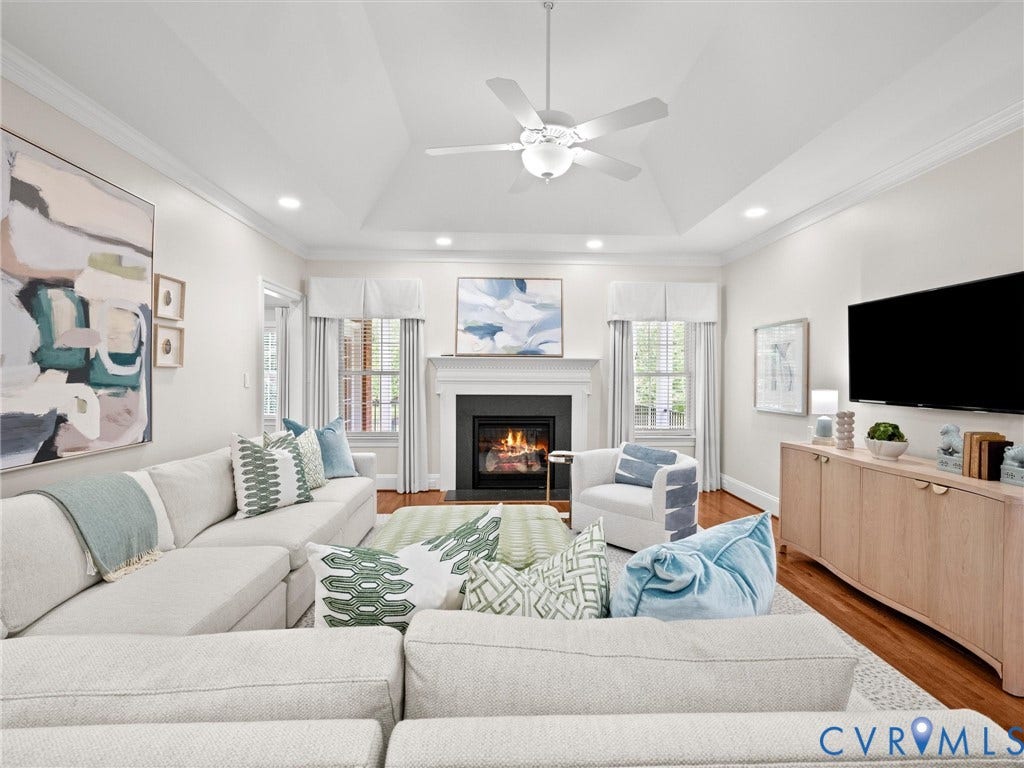 Tray ceiling with a ceiling fan, recessed lighting, hardwood flooring, and a fireplace with a mantel