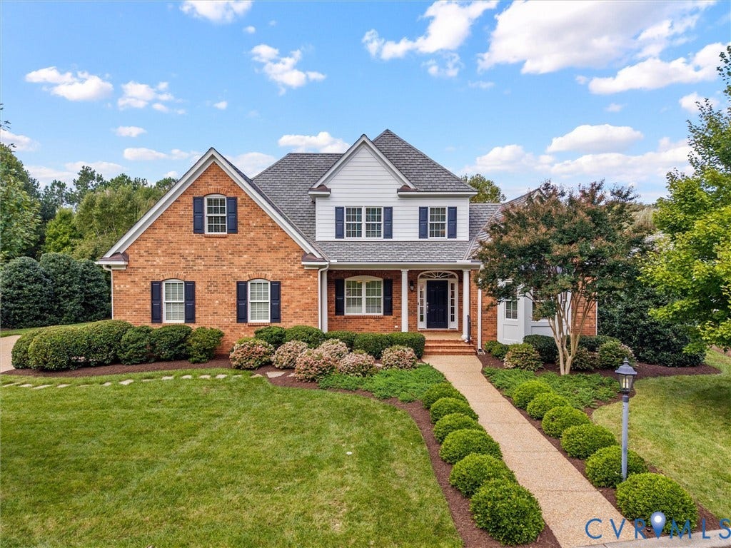 Brick and siding exterior with dark shutters, gabled roofline, and mature landscaping