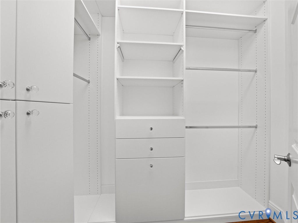 White built-in closet system featuring multiple shelves, drawers, and hanging rods