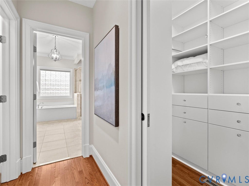 Hallway featuring wood-finish flooring, built-in shelving, and drawers with polished hardware