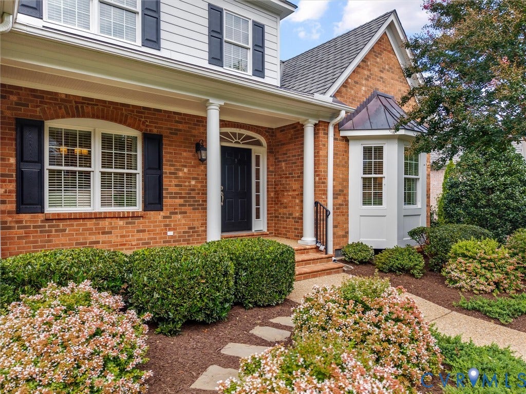 Brick facade with white siding accents and dark shutters