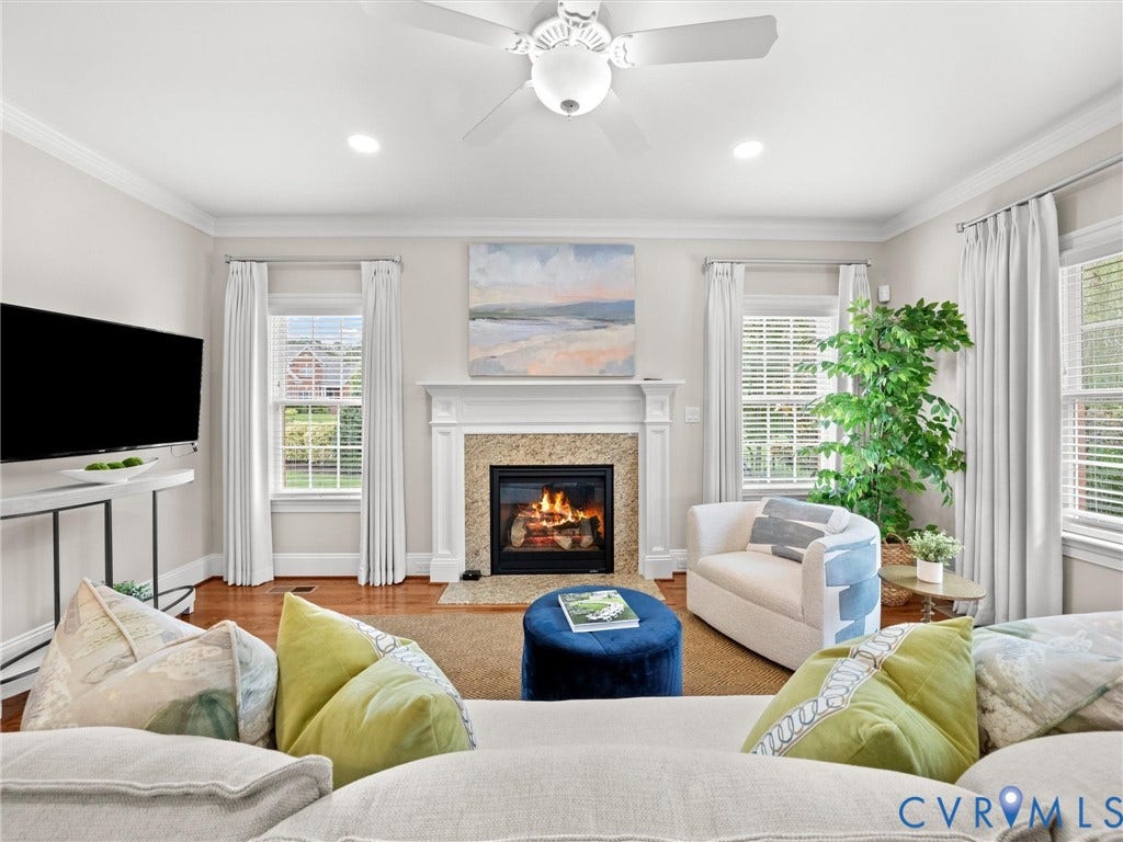Hardwood flooring, recessed lighting, crown molding, fireplace with stone surround and white mantel, and ceiling fan