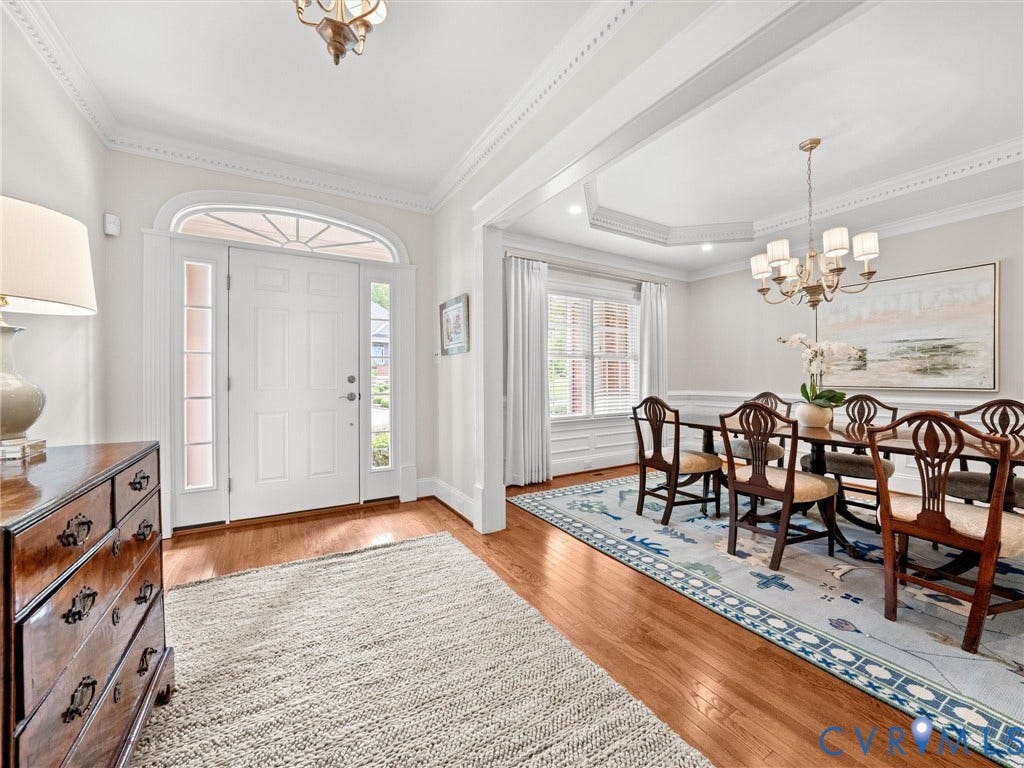 Hardwood flooring, crown molding, double front entry doors with sidelights, arched transom window, and a tray ceiling