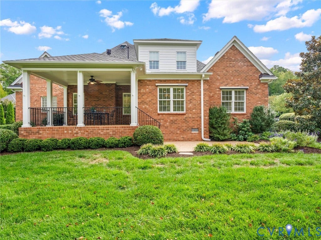 Brick exterior featuring a covered porch with white columns, black railings, and a ceiling fan