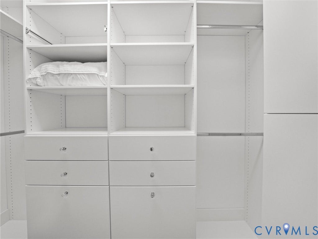 Built-in closet system featuring multiple shelving units, integrated drawers with clear knobs, and hanging rods