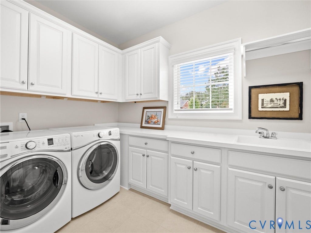 White shaker-style cabinetry, white countertops, built-in sink, and window with blinds