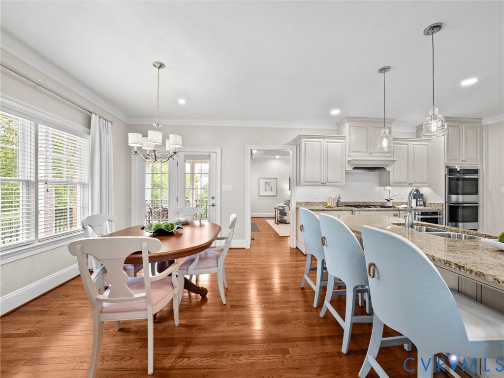 Hardwood flooring, kitchen island with granite countertop, stainless steel appliances, white cabinetry, and French doors