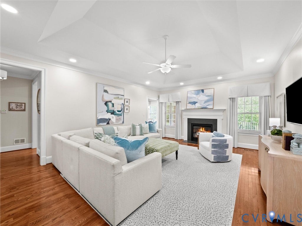 Vaulted ceiling with recessed lighting, wood-finish flooring, fireplace with mantel, ceiling fan, and multiple windows