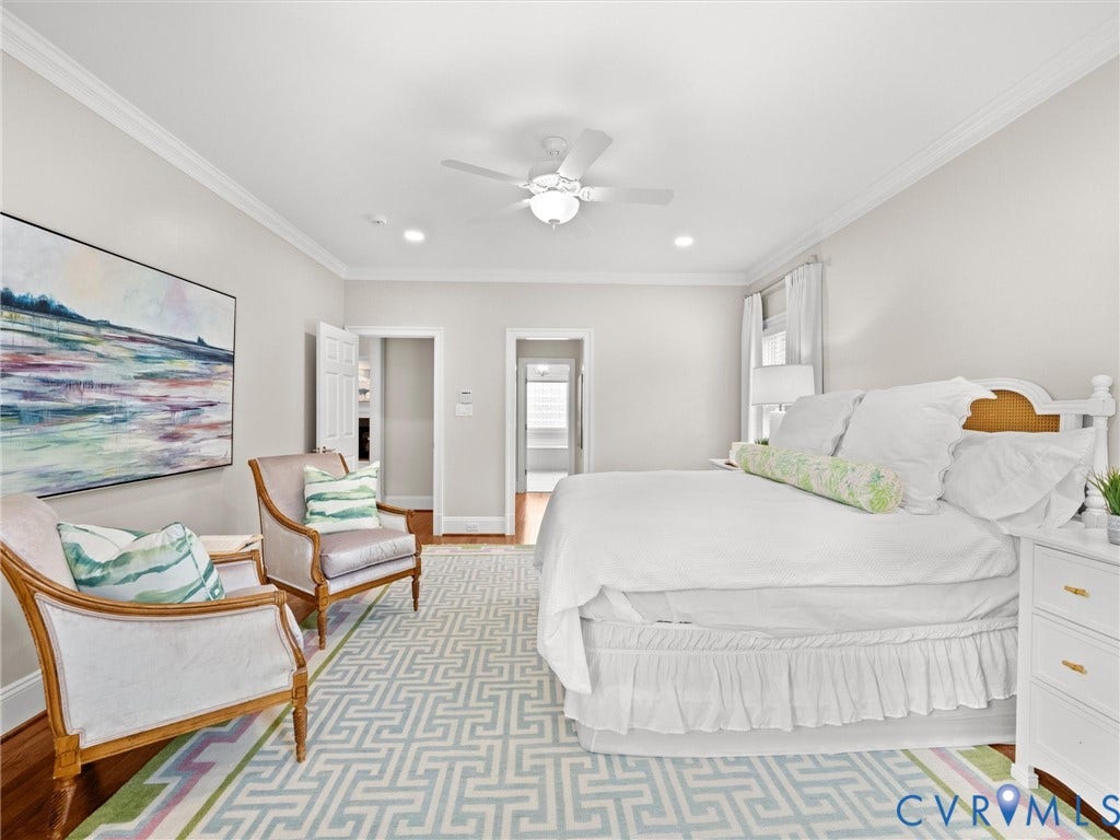 Warm wood-finish flooring, crown molding, a ceiling fan, and recessed lighting enhance this bright space