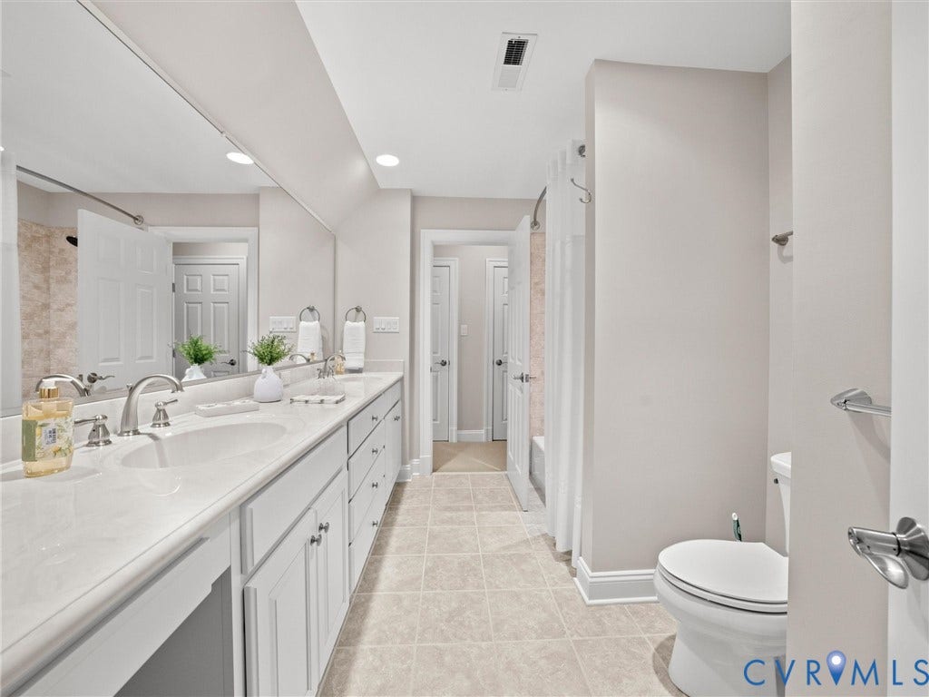 Dual vanity with white cabinetry, integrated sinks, and polished chrome hardware
