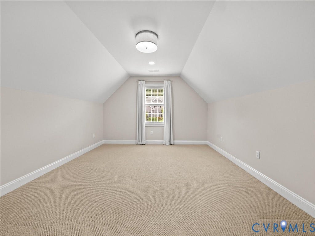 Carpeted room with a central flush mount light fixture, recessed lighting, and a single window with white trim