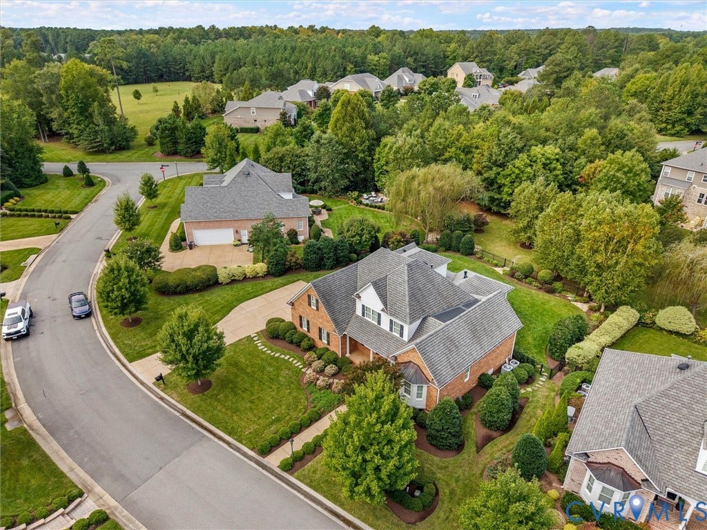 Brick exterior residence featuring a covered front porch, a gabled roof, and established landscaping