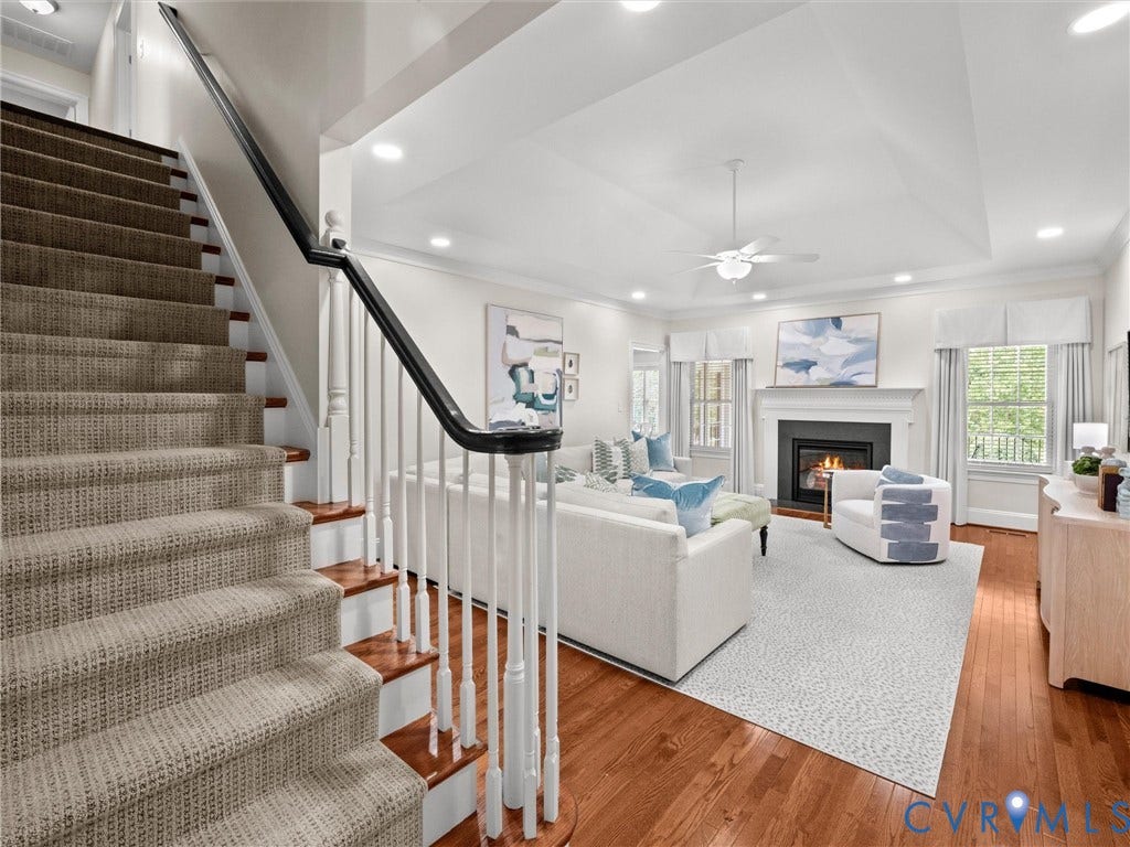 Hardwood flooring, carpeted staircase with white balusters, fireplace with mantel, recessed lighting, and a ceiling fan