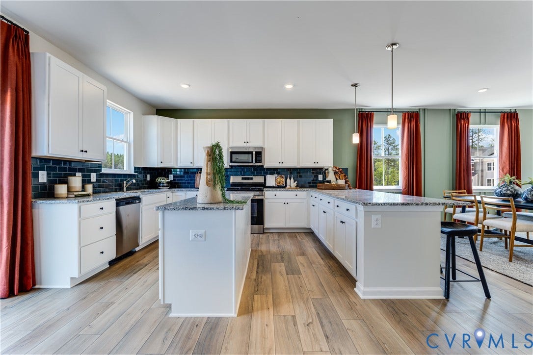 8708 Pullman Lane, Chesterfield, VA 23832 Spacious kitchen featuring two islands, white cabinetry, dark subway tile backsplash, stainless steel appliances, and light wood-finish flooring