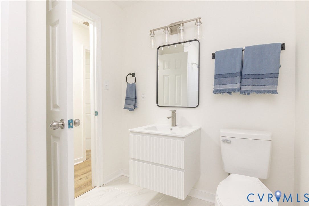 6015 Seaman Road, Westover, Richmond, VA 23225 Wall-mounted floating vanity with integrated sink, rectangular framed mirror, and brushed nickel fixtures