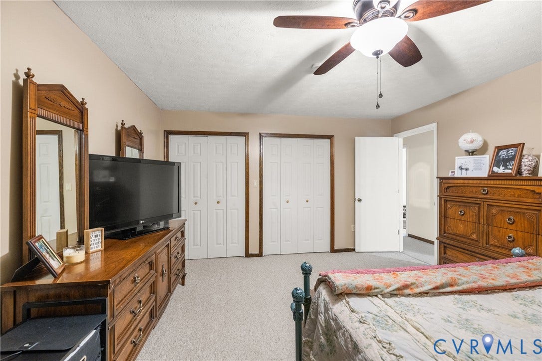 Neutral wall color, ceiling fan with integrated lighting, two sets of bi-fold closet doors, and light-colored carpeting