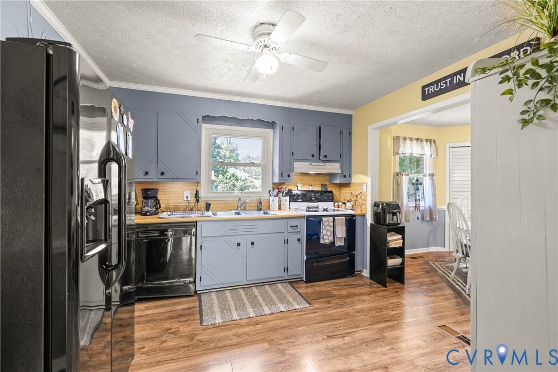 Kitchen featuring wood-finish flooring, light blue cabinetry, a ceiling fan, and a pass-through opening to an additional room