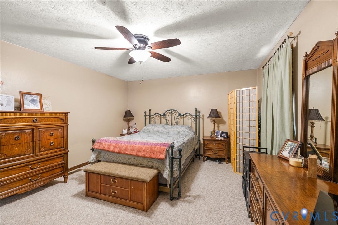 Beige wall paint, light-colored carpet flooring, and a ceiling fan with integrated lighting
