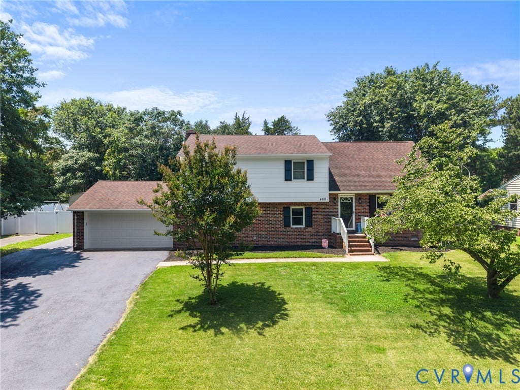 Brick and siding exterior with a multi-level roofline, attached two-car garage, and a paved driveway