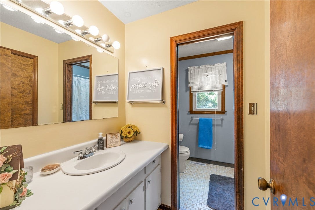 Bathroom featuring a vanity with an integrated sink, a large mirror, and overhead lighting