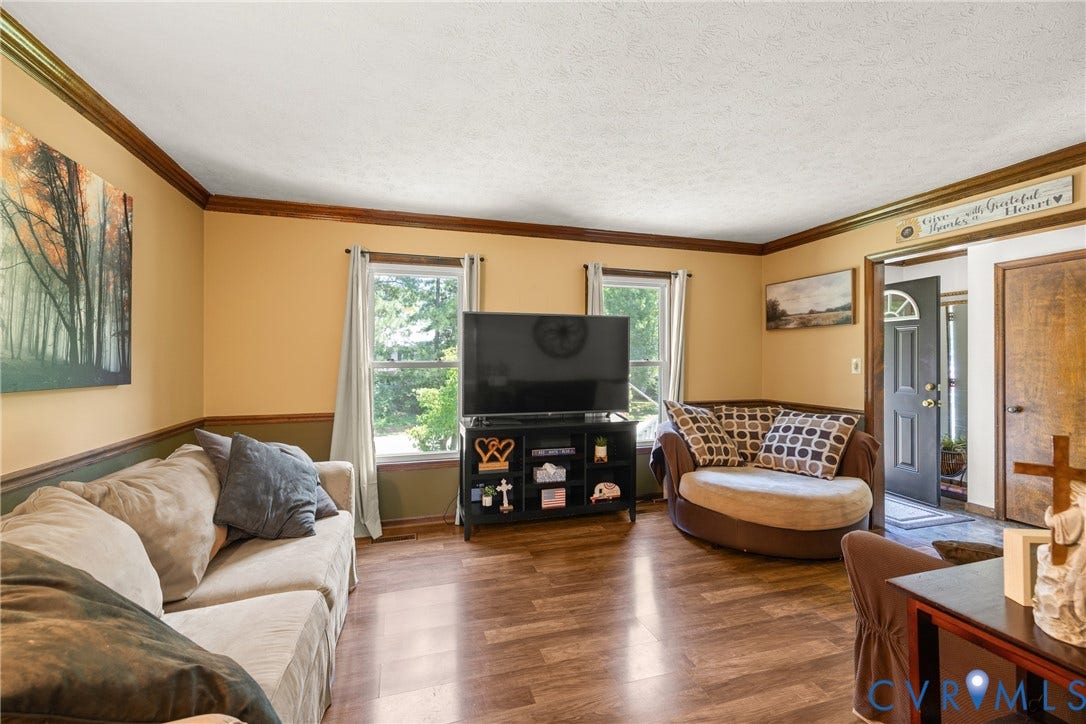 Wood-finish flooring throughout, crown molding, two-tone wall treatment, and a paneled front entry door