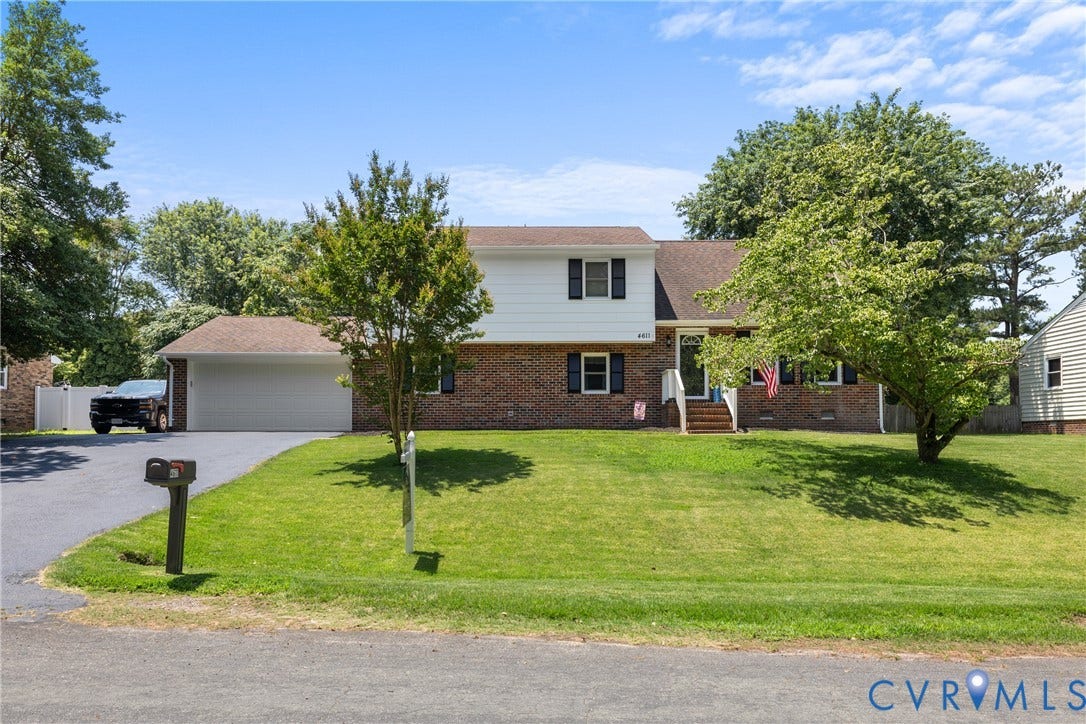 Brick and siding exterior with a pitched roof, attached garage, and a concrete pathway leading to the entry